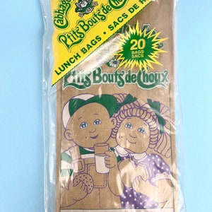 May include: A package of 20 brown lunch bags featuring Cabbage Patch Kids characters. The bags are printed with the text "Little Bouts de Choux" and "Lunch Bags - Sacs de Repas".