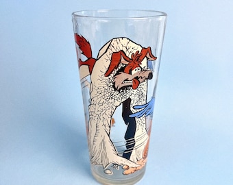 May include: A clear glass featuring a cartoon image of Wile E. Coyote from the Looney Tunes cartoon series. The coyote is shown in a frustrated pose, with his tongue sticking out.