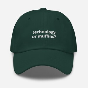May include: A dark green baseball cap with the text "technology or muffins?" embroidered in white. The cap has a curved brim and a button on top. This hat is a fun accessory for anyone.