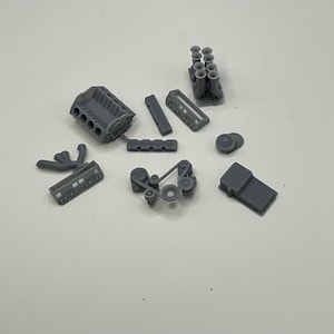 May include: A set of gray plastic model car engine parts, including the engine block, intake manifold, exhaust manifold, and other accessories.