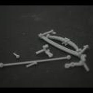 Peut inclure: Un ensemble de pièces de voiture modèle en plastique gris, comprenant un essieu avant, des bras de suspension et diverses bielles.
