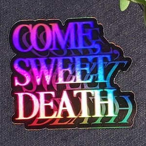 Puede incluir: Una pegatina holográfica con el texto "COME SWEET DEATH" en colores arcoíris.
