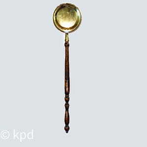 May include: A vintage brass ladle with a round bowl and a long, dark wooden handle. The handle features decorative turned details. The ladle is likely used for serving or cooking and has a classic, antique aesthetic.