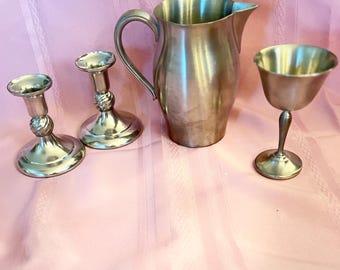 Elegante colección ecléctica de peltre vintage: cáliz, candelabros y jarra.