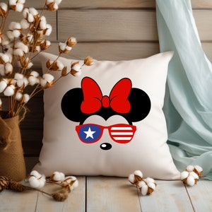 May include: White pillow with a red, white, and blue cartoon mouse wearing sunglasses. The mouse has a red bow on its head.
