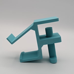 May include: A light blue plastic clamp with a threaded screw. The clamp has a curved arm that extends out from the side.