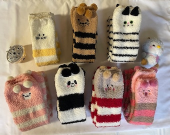 Puede incluir: Ocho pares de calcetines rayados peludos con caras de animales. Los calcetines son de varios colores, incluyendo rosa, blanco, negro, marrón y rojo. Cada calcetín tiene una cara de animal diferente, incluyendo un gato, un panda, un cerdo y un conejito.