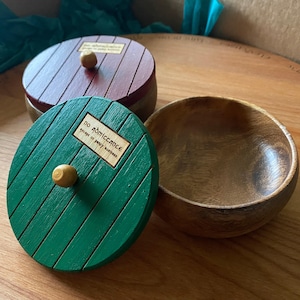 Op de afbeelding: Houten kommen en dozen met deksel met een Hobbit-deurthema. Het groene deksel heeft de tekst "NO ADMITTANCE except on party business". Het andere deksel is bordeauxrood. De kom is van hout.