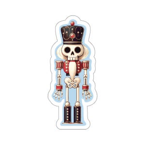 May include: A sticker featuring a skeleton nutcracker design. The nutcracker has a black crown, red and white accents, and a skeletal body. The sticker is outlined in light blue.