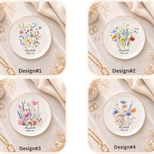 May include: Four round white ceramic trinket dishes with gold rims, each featuring a unique watercolour wildflower bouquet illustration. Below the floral designs, the text reads Elizabeth Chapter 60 in a black script and serif font combination.