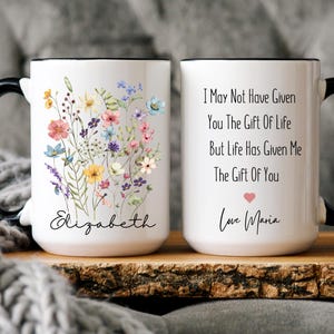 May include: White ceramic mug with a black handle and rim. One side features a floral design with colourful flowers and the name "Elizabeth". The other side has the text "I May Not Have Given You The Gift Of Life But Life Has Given Me The Gift Of You" and "Love Maria".