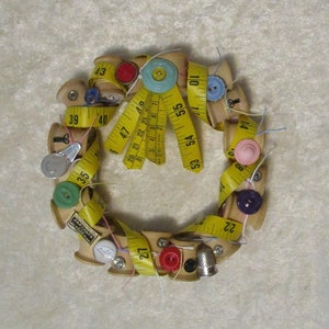 Sewing themed wreath using spools, tape measure, buttons and other sewing items.