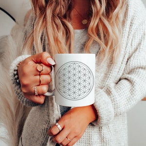 May include: White ceramic mug with a black and white geometric flower of life design.