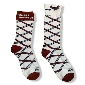 May include: A pair of white knee-high socks with a red and black plaid pattern. One sock has the text "Guess What?" on the cuff and the other sock has a small image of a chicken on the cuff. The socks have the text "Socks Nidi" on the bottom.