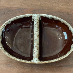 Könnte beinhalten: Eine ovale Servierplatte aus Keramik, die in zwei Abschnitte unterteilt ist, mit einem gesprenkelten braunen und weißen Überzug.