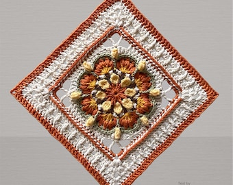 Könnte beinhalten: Quadratische Häkeldecke in Rautenform. Das zentrale Blumenmuster verwendet orange, gelbe und grüne Garne, umrahmt von einem weißen und orangefarbenen Rand. Der Text "Test by Hooked on Häkelmaschen" ist sichtbar. Das Design ist detailliert.