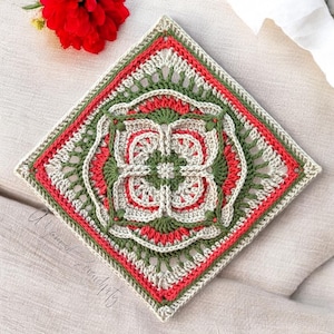Peut inclure: Un carré crocheté avec un motif géométrique dans les tons de vert, corail et beige. Le carré a une bordure de corail et de beige.