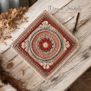 May include: A crocheted square with a circular design in the center. The square is made with beige, brown, red, and gray yarn. The text "A Yarn of Serendipity" is in the top right corner of the image.