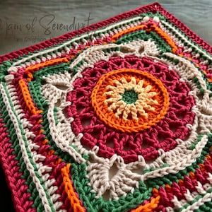 May include: A square, handmade crochet piece in a vibrant color palette. The design features concentric circles and geometric patterns in shades of red, orange, green, and cream. The text "A Yarn of Serendipity" is visible in the upper left corner.