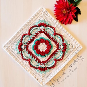 Può includere: Un quadrato di uncinetto bianco con un motivo floreale rosso, bianco e turchese al centro. Il testo "A Yarn of Serendipity" è scritto nell'angolo in basso a destra del quadrato.
