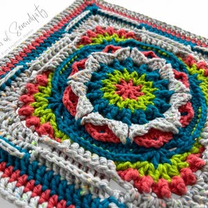 Könnte beinhalten: Ein gehäkeltes Quadrat mit einem bunten kreisförmigen Design in der Mitte. Das Quadrat ist in verschiedenen Farben gearbeitet, darunter Türkis, Grün, Rosa und Grau. Das kreisförmige Design ist mit verschiedenen Maschen gearbeitet, darunter feste Maschen, halbe Stäbchen und Stäbchen.