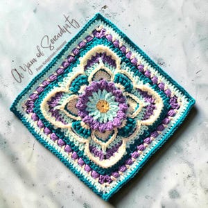 Puede incluir: Un motivo de ganchillo cuadrado con una flor central amarilla, azul claro y morada rodeada por capas de hilo crema, verde azulado y morado en un patrón geométrico. El texto A Yarn of Serendipity Pam Knighton-Haener es visible.