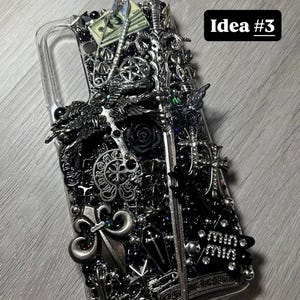 May include: A clear phone case heavily embellished with silver and black decorative elements, including crosses, fleur-de-lis, a rose, and a miniature sword. The text "Idea #3" is visible.