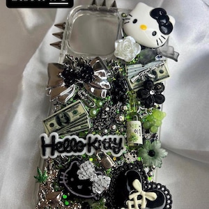 May include: Clear phone case decorated with a Hello Kitty figure, money, a bow, and other embellishments. The case has a studded border and the text "Idea #8" in the upper left corner. The words "Hello Kitty" are also visible.