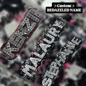 May include: Three custom bedazzled name accessories. The names are spelled out in silver rhinestones on a dark background. The text "Custom Bedazzled Name" is in a black rectangle.