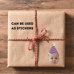 May include: A wrapped package in brown paper tied with red and cream twine. The text "CAN BE USED AS STICKERS" is printed on the package. A sticker of a baby wearing a party hat is on the package.