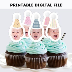 Könnte beinhalten: Eine druckbare digitale Datei mit Cupcake-Aufsteckern, die Babygesichter mit bunten Partyhüten und Bommeln zeigen. Die Hüte haben verschiedene Muster wie Blumen, Punkte, Karos, Streifen und vertikale Linien. Die Aufstecker stecken in Cupcakes.