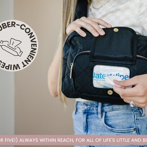 Mom wearing black Jetsetter Mini crossbody diaper bag with easy-access wipes pocket.