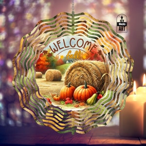 May include: A metal wind spinner with a fall theme. The spinner features a watercolor painting of hay bales, pumpkins, and fall leaves. The text "Welcome Fall" is written in a white circle on the spinner.