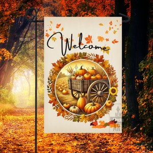 Puede incluir: Una bandera de jardín de bienvenida con un tema otoñal. La bandera presenta una corona de hojas de otoño que rodea un carro lleno de calabazas. El carro es tirado por un caballo y el texto "Bienvenido" está impreso en una fuente decorativa.