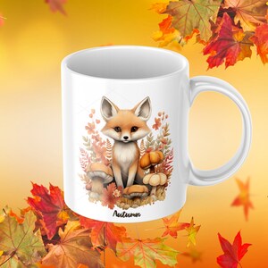 May include: White ceramic mug with a cartoon fox sitting on mushrooms and surrounded by autumn leaves. The mug has the word "Autumn" printed on the bottom.