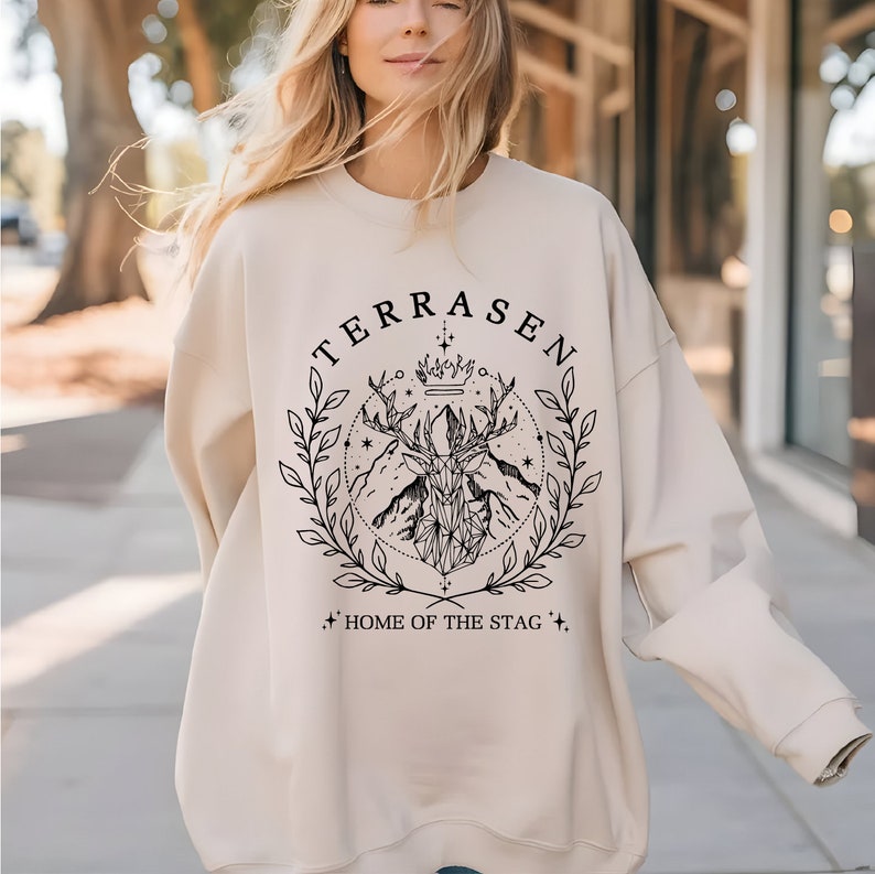 a woman wearing a sweatshirt that says terrasen home of the stag