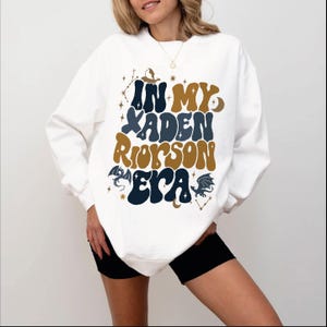 a woman wearing a white sweatshirt and black shorts
