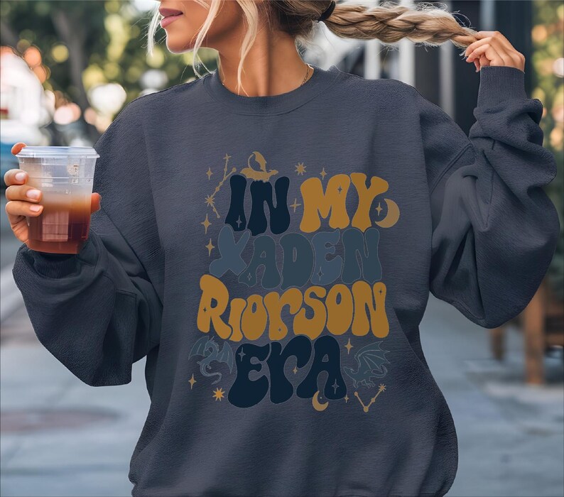 a woman holding a drink and wearing a sweatshirt