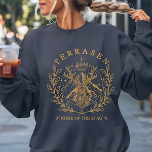 a woman holding a drink and wearing a sweatshirt