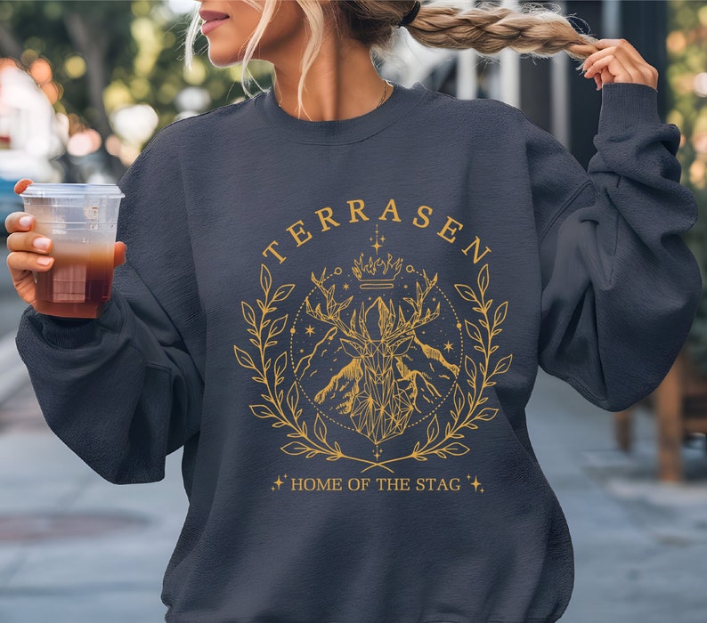 a woman holding a drink and wearing a sweatshirt