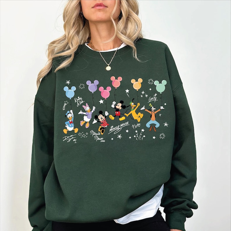 A woman wearing a green sweatshirt with a Disney character design on it.