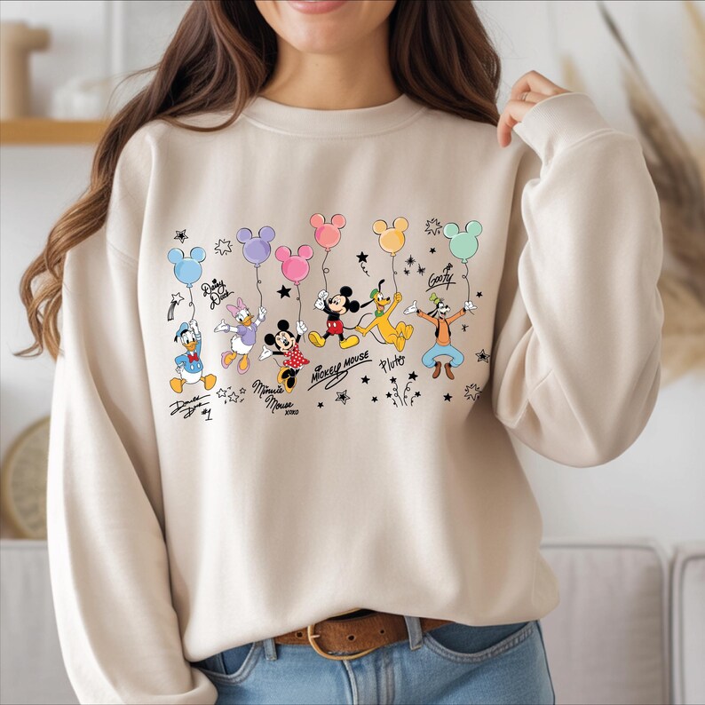 A woman wearing a white sweatshirt with a graphic of Disney characters and balloons printed on it.