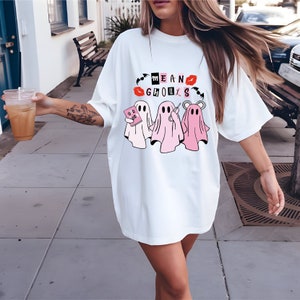 a woman walking down a sidewalk wearing a white shirt dress