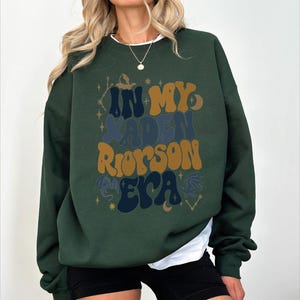 a woman wearing a green sweatshirt and black shorts