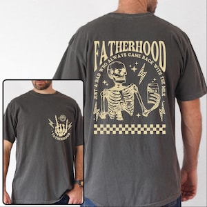 May include: Dark gray t-shirt with a skeleton graphic holding a milk carton, and the text "FATHERHOOD". The back of the shirt has the text "JUST A DAD WHO ALWAYS CAME BACK WITH THE MILK". The shirt also has a small graphic on the front.