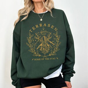 a woman wearing a green sweatshirt and black shorts