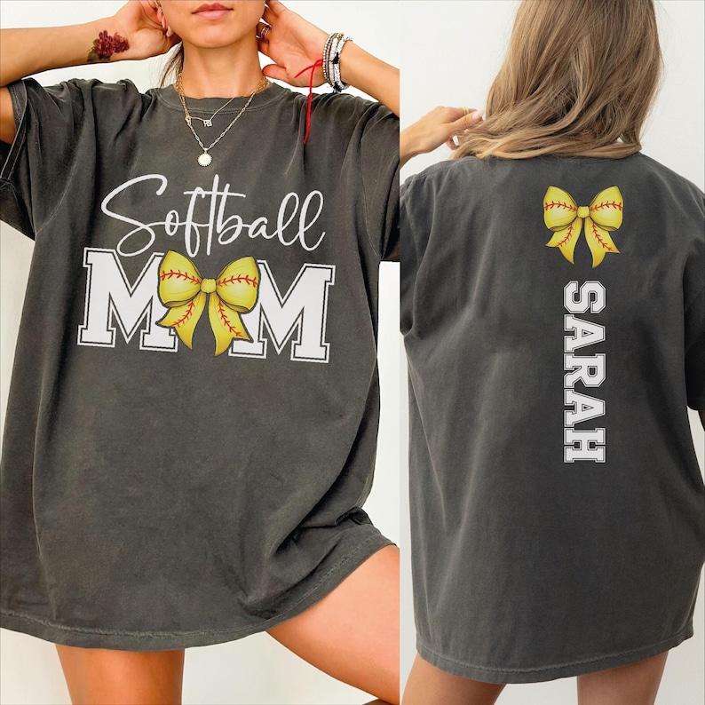 A woman wearing a gray t-shirt with the text "Softball Mom" and a yellow bow on the back.