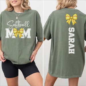 A woman wearing a green t-shirt with the text "Softball Mom" printed on it, along with a yellow bow.