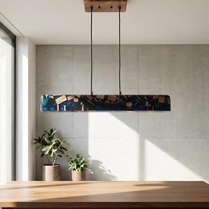 Può includere: Un lampadario rettangolare con un piano in legno e un corpo blu scuro e color legno. La luce è sospesa a due cavi neri. L'apparecchio è sospeso sopra un tavolo da pranzo in legno in una sala da pranzo moderna.