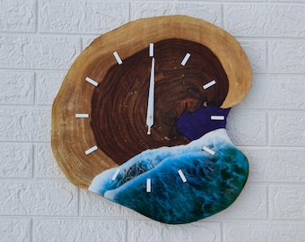 May include: A unique wall clock crafted from a cross-section of a tree trunk. The clock face features a dark brown center, a light brown outer ring, and a blue and white resin wave design. White rectangular markers indicate the hours.